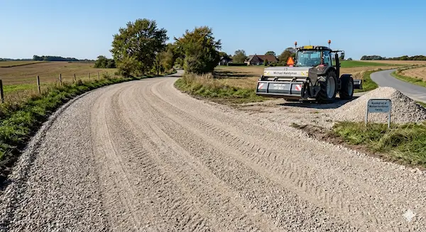 Traktor vedligeholder grusvej på landet
